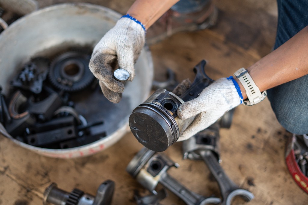 Gloved hands inspecting an engine piston